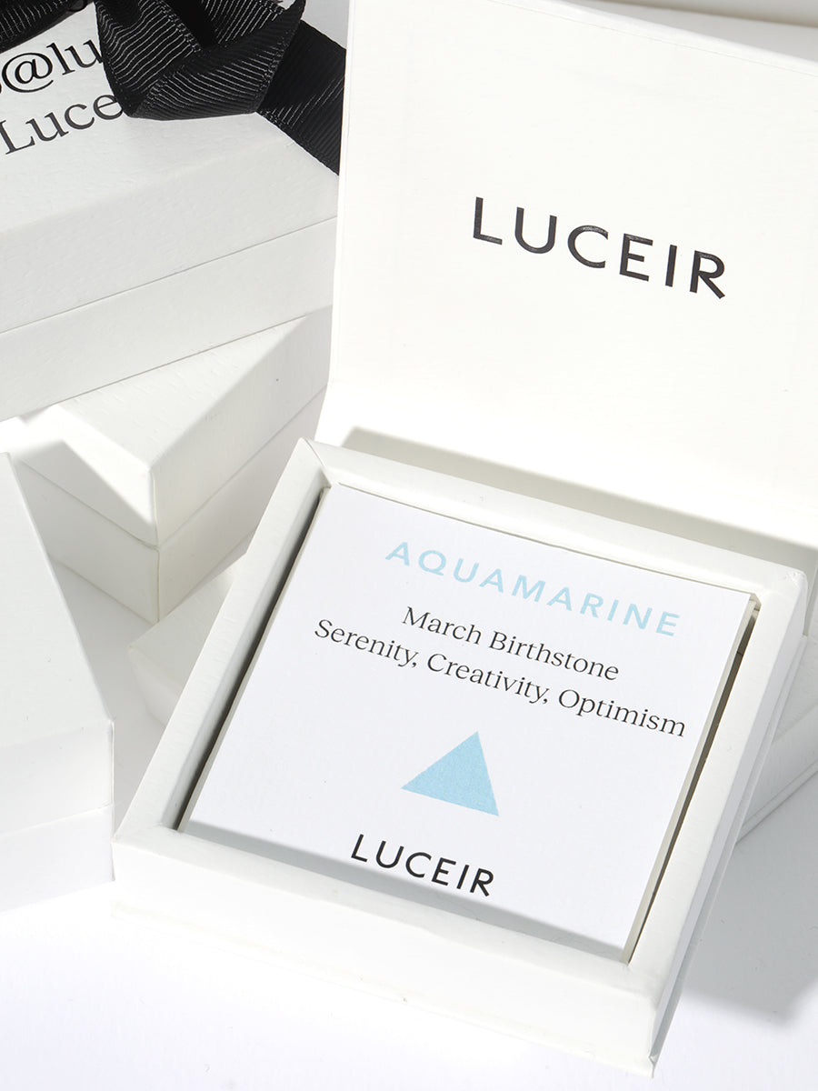 Luceir white packaging card set in a box saying Aquamarine, March Birthstone, Serenity, Creativity, Optimism followed by a baby blue triangle symbol underneath with Luceir logo at the bottom