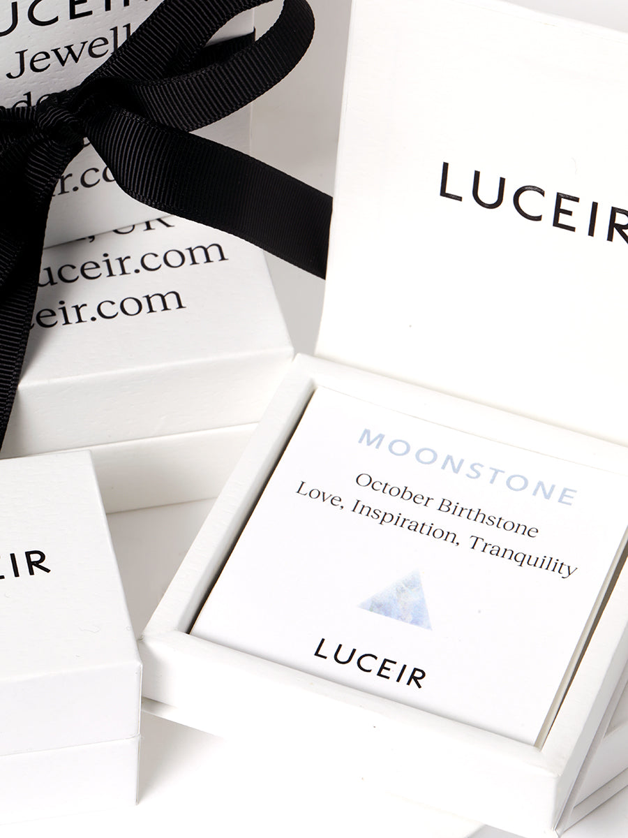 Luceir white packaging card set in a box saying Moonstone, October Birthstone, Love, Inspiration, Tranquility followed by a silver iridescent triangle symbol underneath with Luceir logo at the bottom