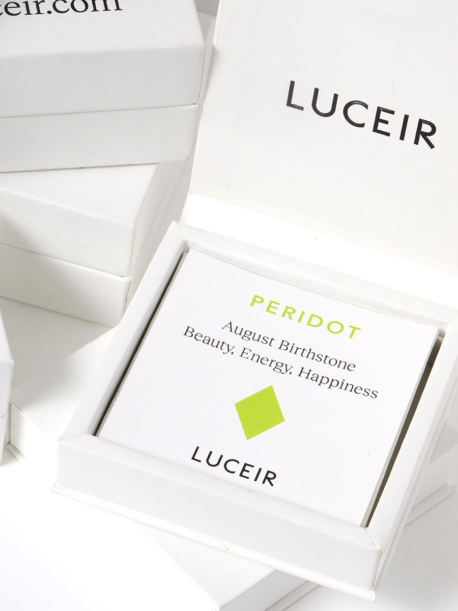 Luceir white packaging card set in a box saying Peridot, August Birthstone, Beauty, Energy, Happiness followed by a light green diamond symbol underneath with Luceir logo at the bottom