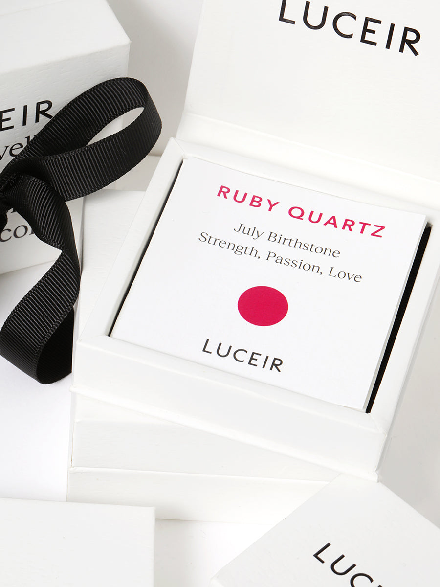 Luceir white packaging card set in a box saying Ruby Quartz, July Birthstone, Strength, Passion, Love followed by a ruby circular dot symbol underneath with Luceir logo at the bottom