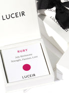 Luceir white packaging card set in a box saying Ruby, July Birthstone, Strength, Passion, Love followed by a ruby dot symbol underneath with Luceir logo at the bottom