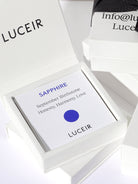 Luceir white packaging card set in a box saying Sapphire, September Birthstone, Honesty, Harmony, Love followed by a blue dot symbol underneath with Luceir logo at the bottom