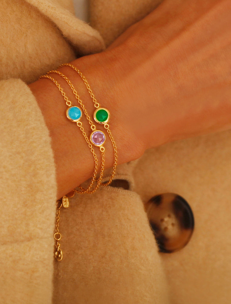 Three different gemstone bracelets worn together on the right wrist green, purple and blue